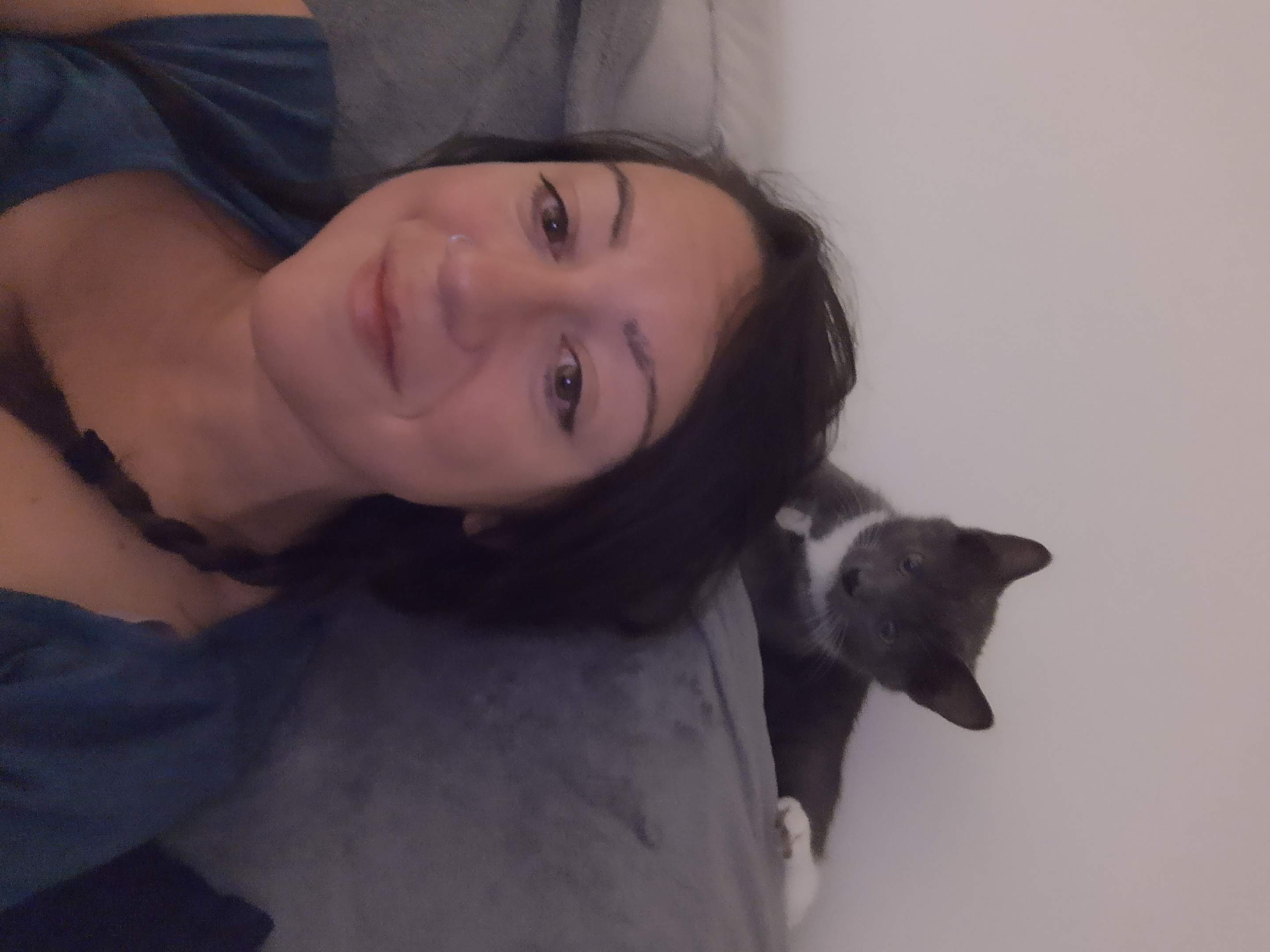 Sam lying back next to a grey and white cat, both facing the camera