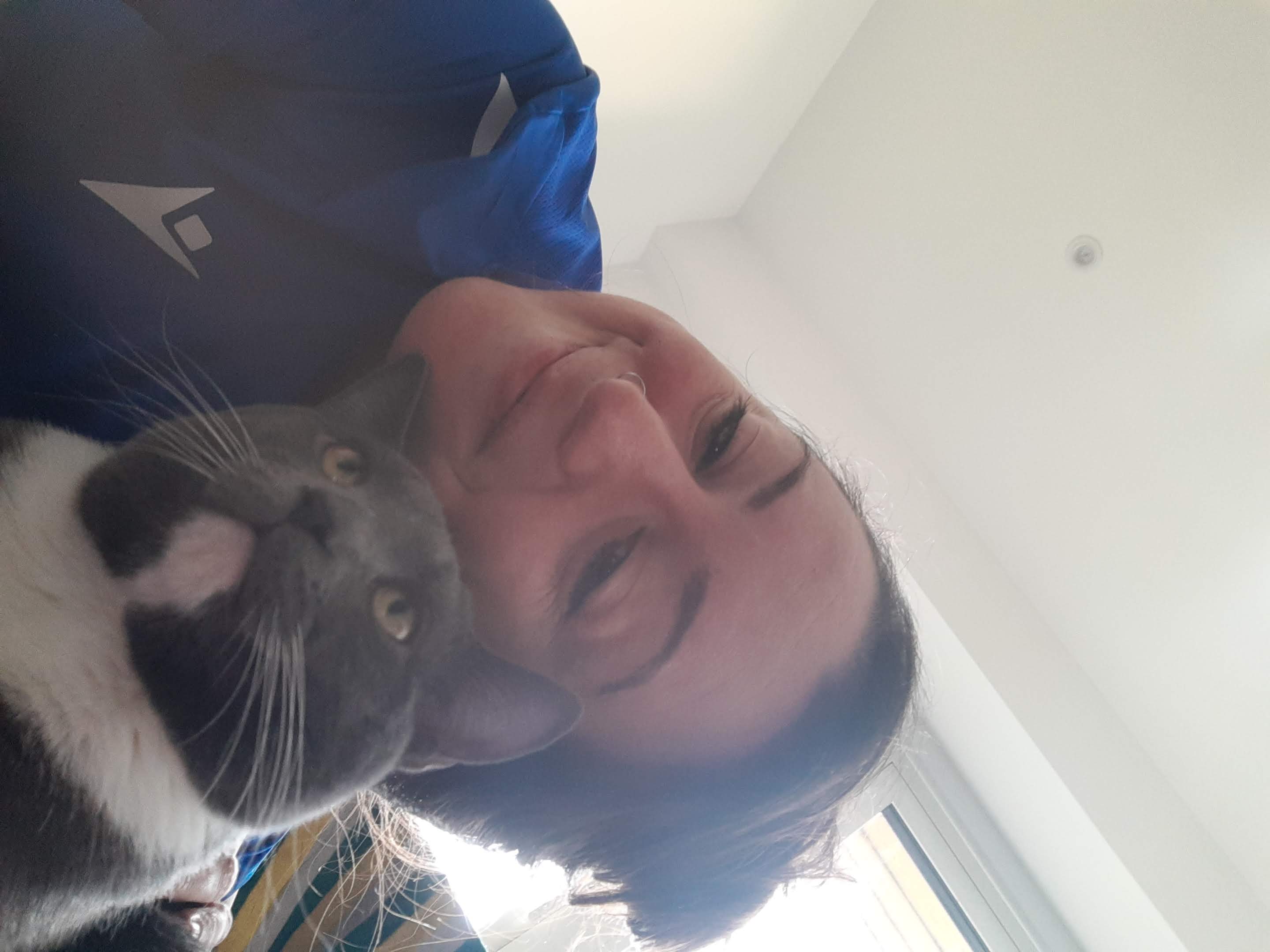 Sam holding her grey and white cat Gnocchi close to her cheek, both looking at the camera